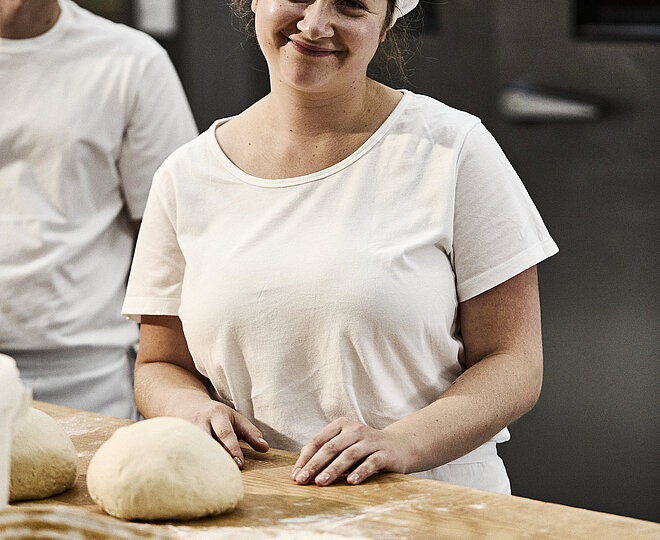 Bäckerin beim Teig Kneten