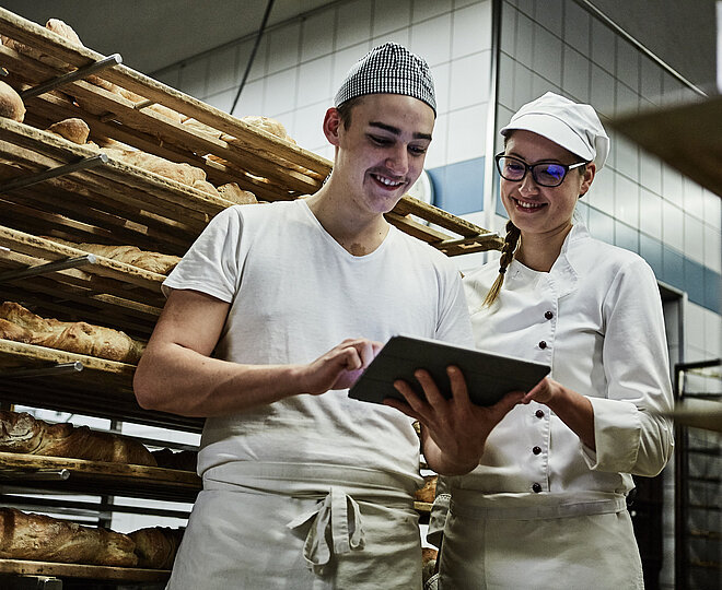Zwei Bäcker besprechen etwas und schauen auf ein Klemmbrett