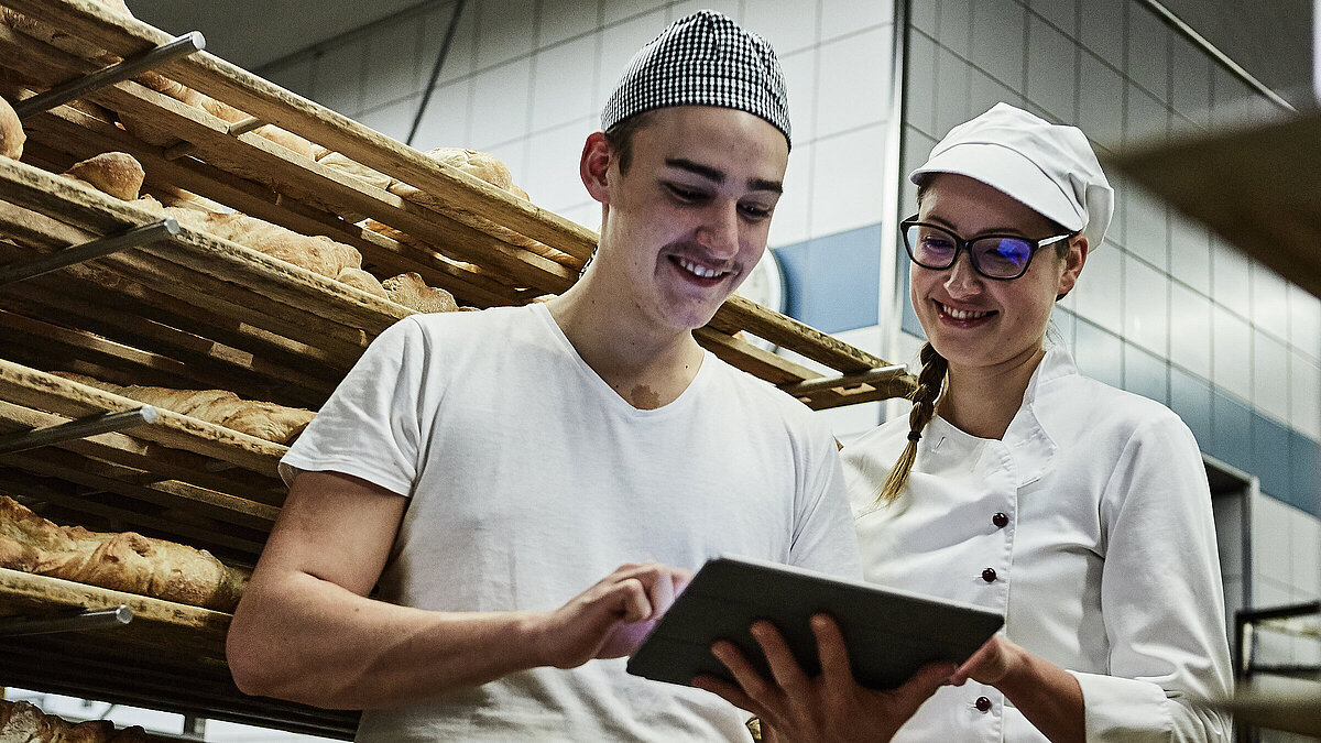Zwei Bäcker besprechen etwas und schauen auf ein Klemmbrett