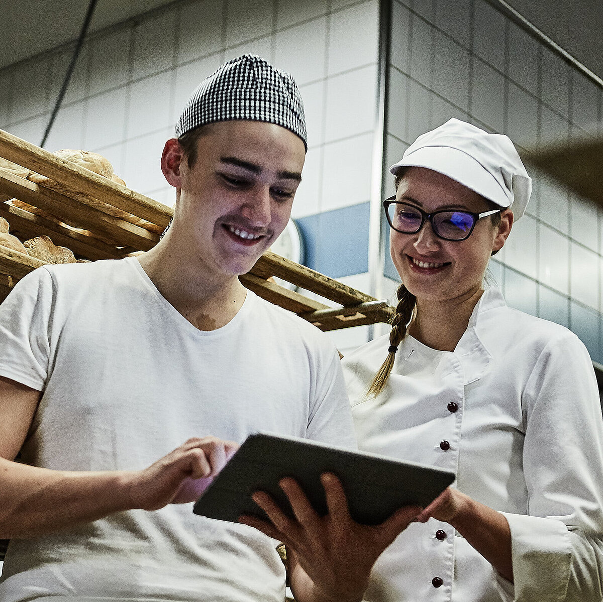 Zwei Bäcker besprechen etwas und schauen auf ein Klemmbrett
