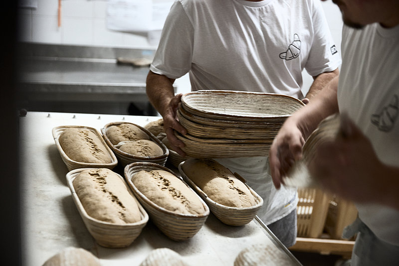 Bäcker mit Broten in Garkörben