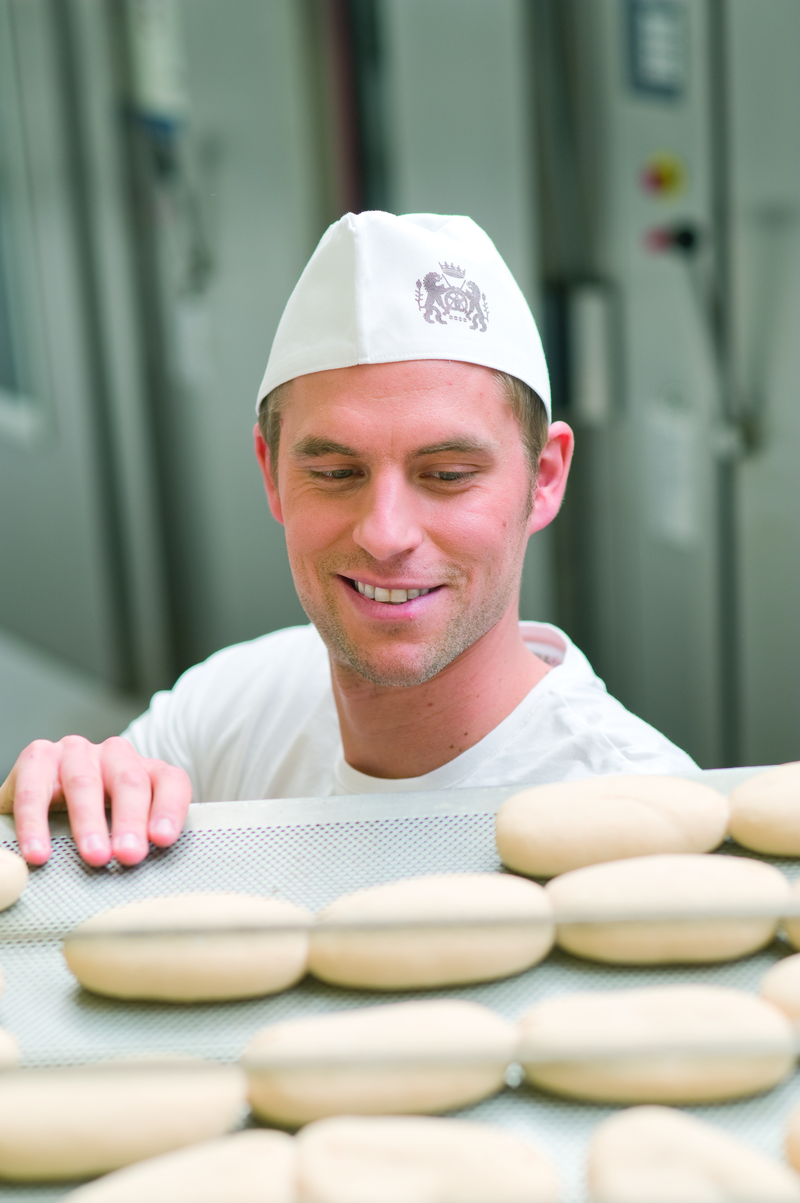 Bäckergeselle begutachtet Brötchenteiglinge