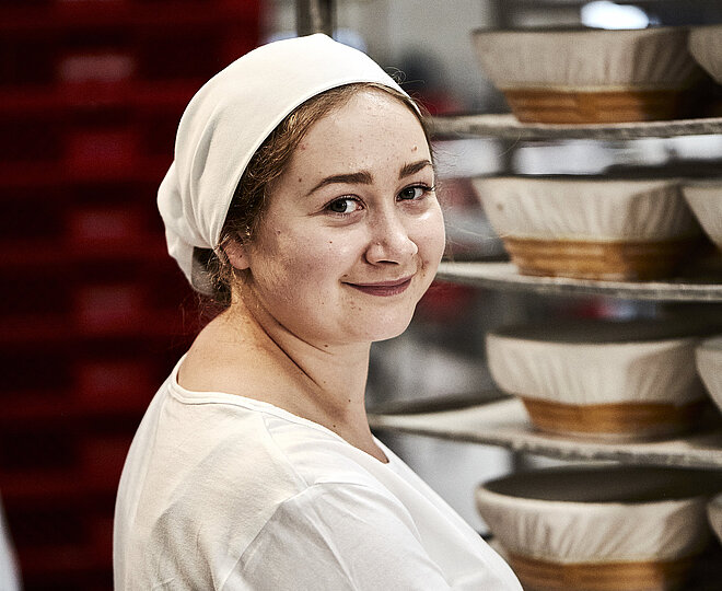 Bäckerin bei der Arbeit, sie lächelt in die Kamera