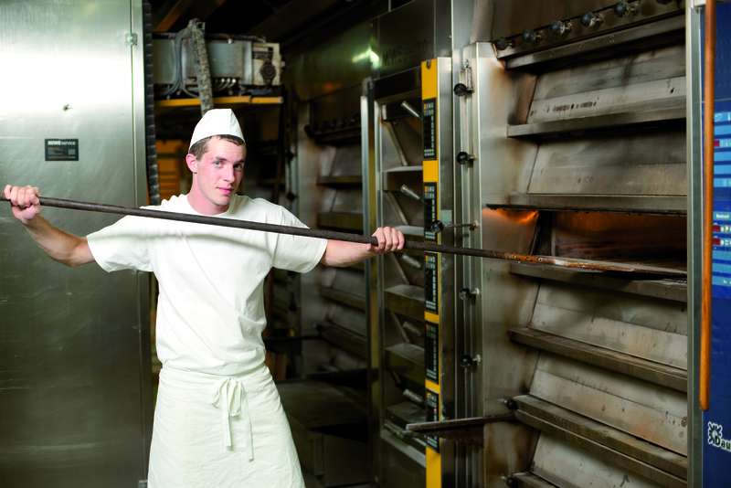 Bäckergeselle am Ofen mit Schieber