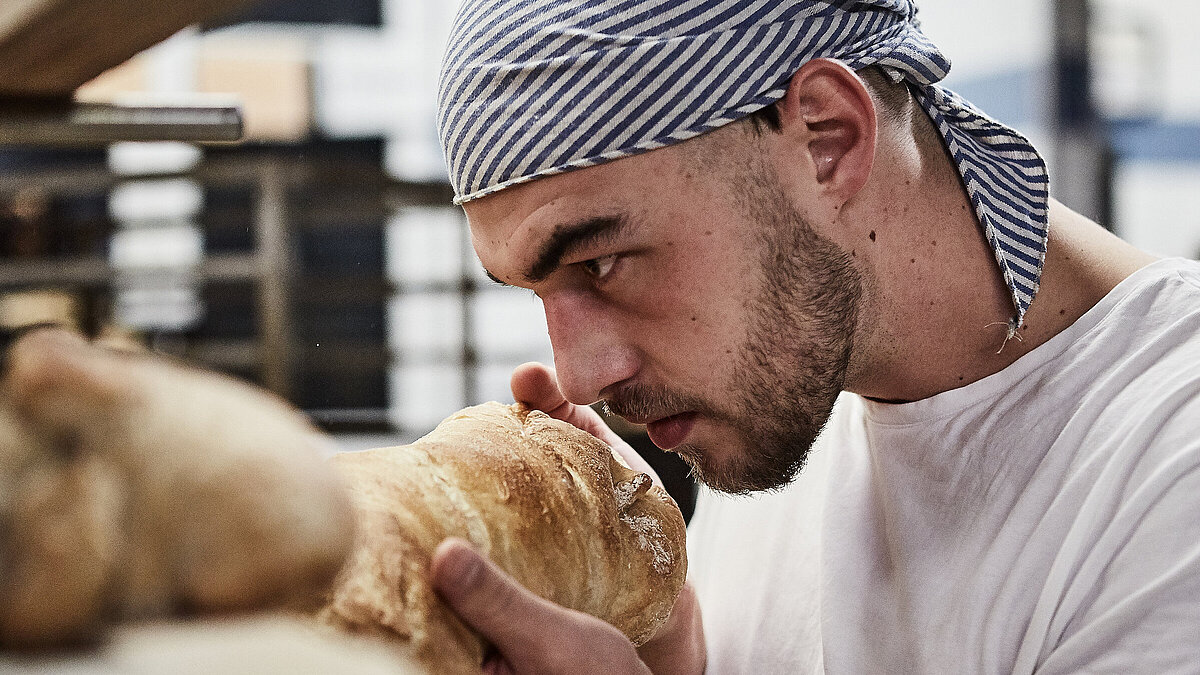 Bäcker riecht an frischen Brötchen