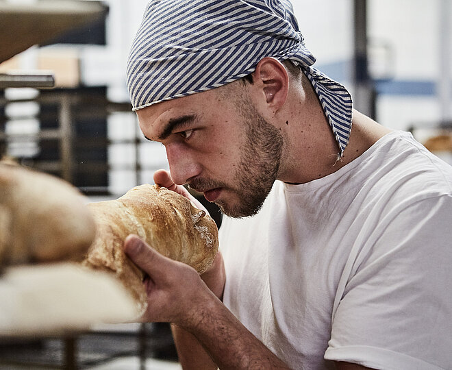 Bäcker riecht an frischen Brötchen