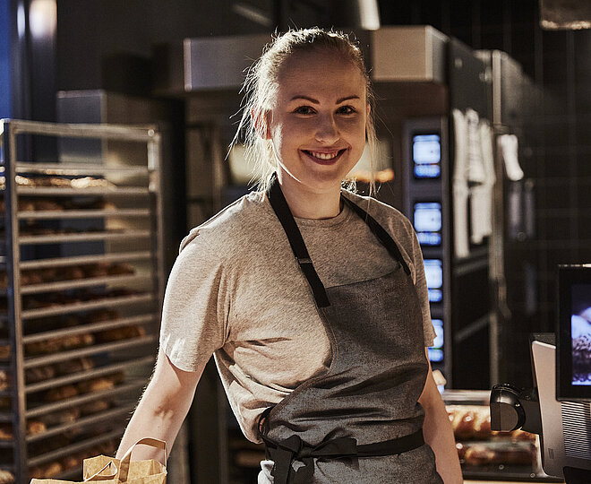 Bäckereifachverkäuferin schaut in die Kamera