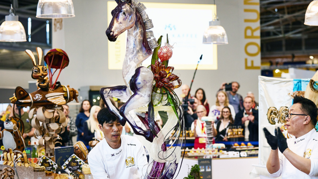 2 Bäcker mit einem Kunstwerk in Form eines Pferdes auf der Iba 2023