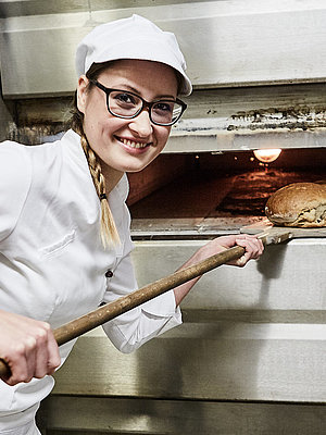 Bäckerin schiebt Brot in den Ofen