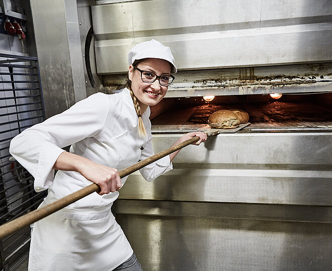 Bäckerin schiebt Brot in den Ofen