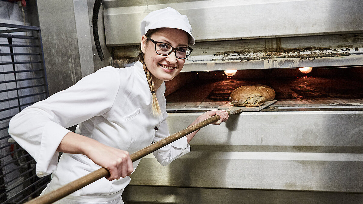 Bäckerin schiebt Brot in den Ofen