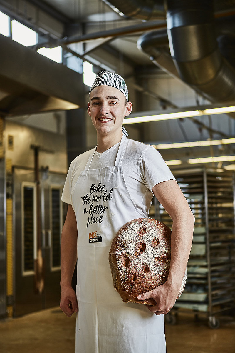 Bäcker-Auszubildender mit Brot in der Hand