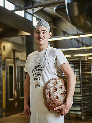 Bäcker-Auszubildender mit Brot in der Hand