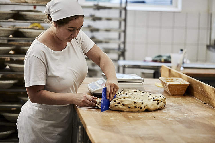 Bäckerin schneidet eine Große Menge Teig in kleine Stücke