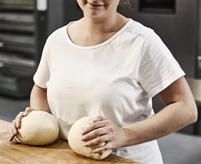Bäckerin beim Teig kneten