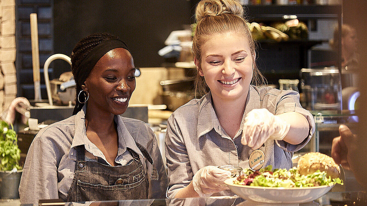 Bäckereifachverkäuferinnen an der Grillecke, bereiten ein Glas vor